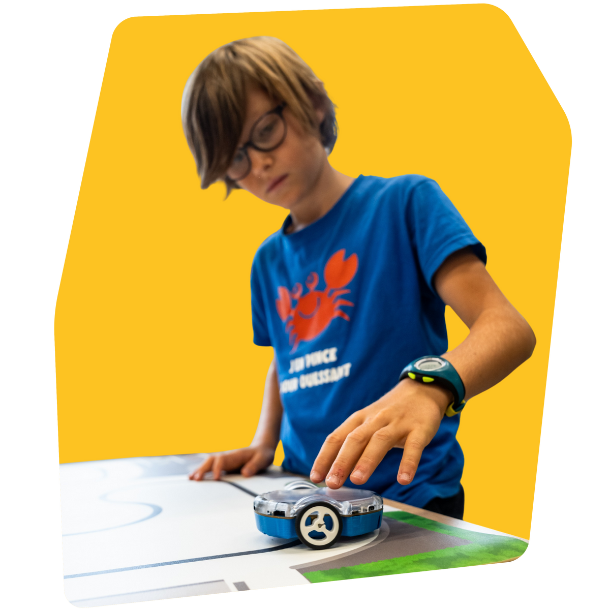 Un enfant penché sur son Eliobot posé sur un tapis de jeu