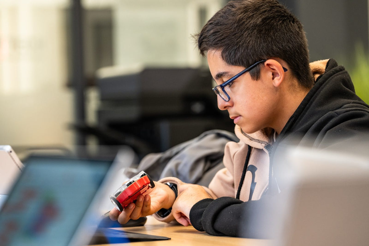 Un adolescent programme son robot Eliobot sur ordinateur pendant un atelier