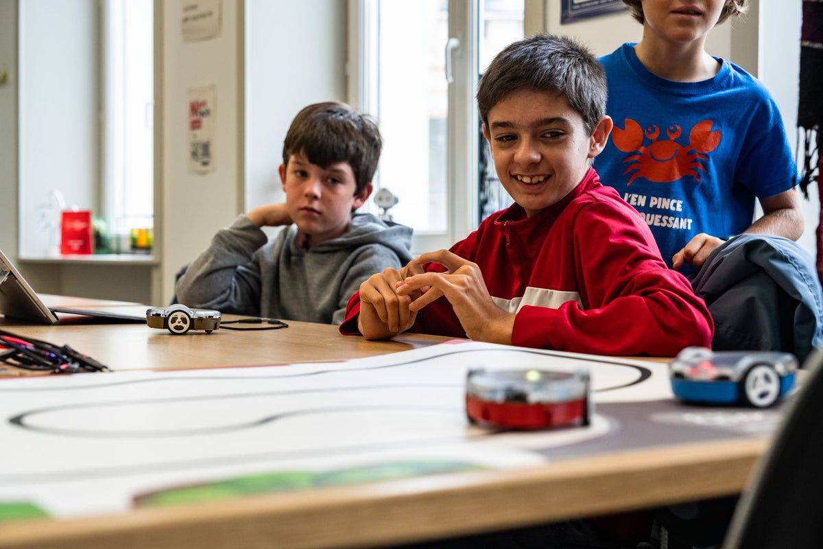 Atelier de robotique : des enfants font rouler leurs robots Eliobot sur un parcours de ligne noire