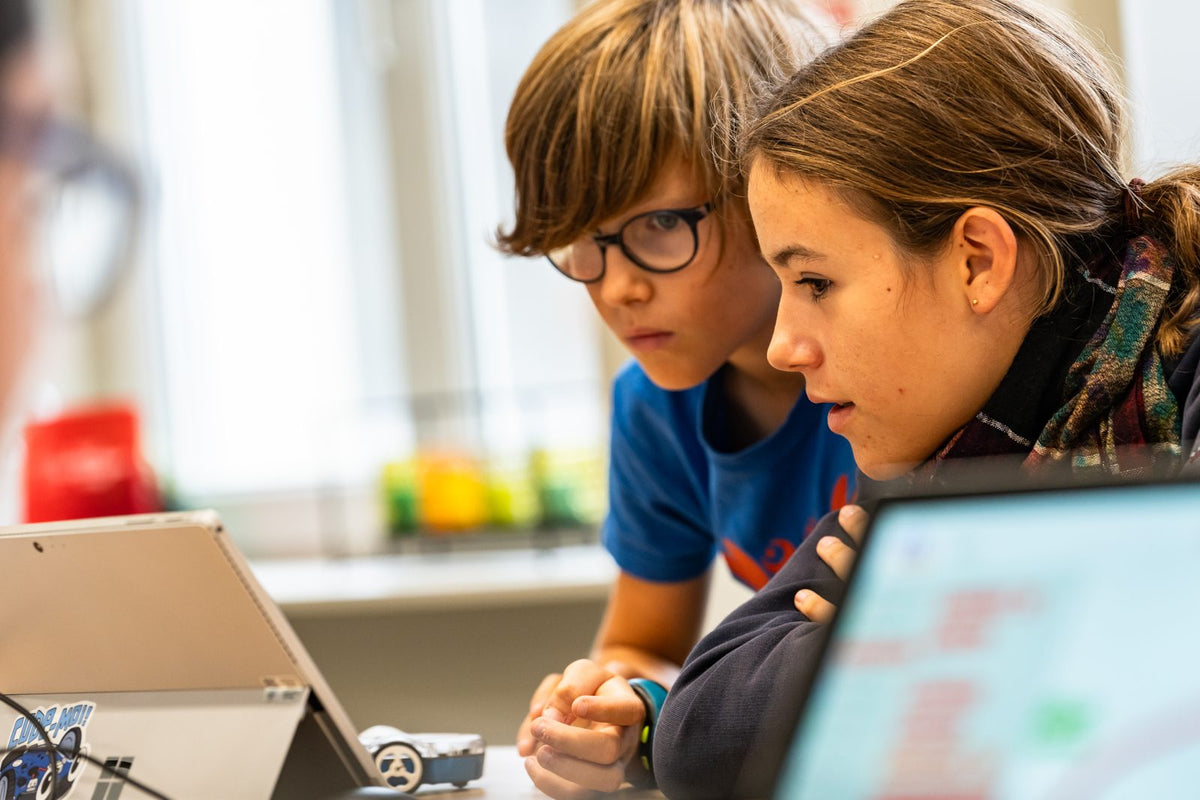 Un garçon et une fille programment ensemble leur robot sur un ordinateur