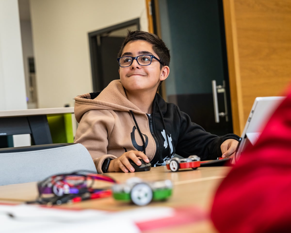 Un enfant en classe observe son Eliobot posé devant lui